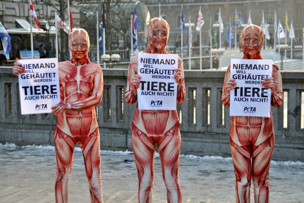 PETA-Demonstrierende in "gehäutet" Morphsuits und mit Schildern.