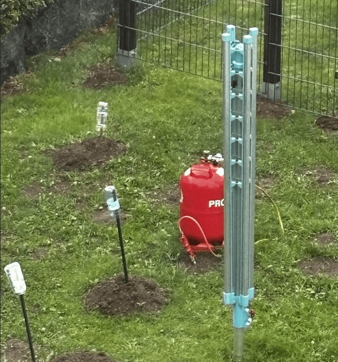 Eine Wiese mit Maulwaurfhügeln und eine Propangasflasche.