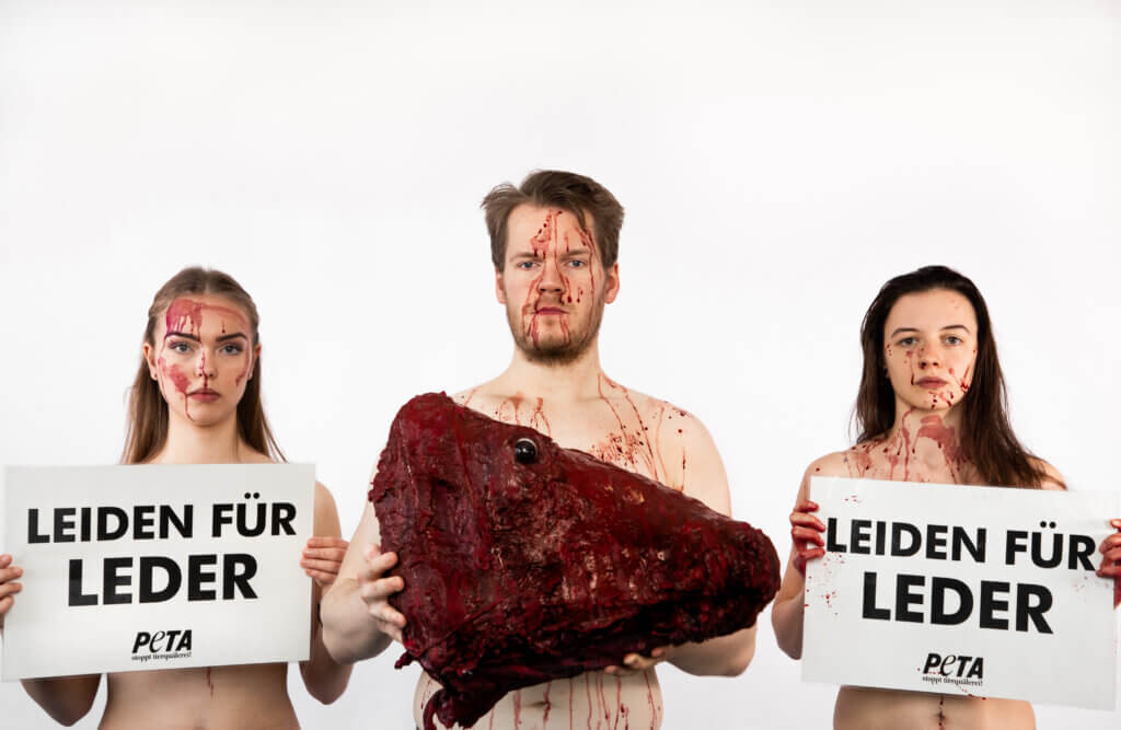 Blutverschmiert und mit „gehäutetem“ Kuhkopf demonstrieren die Aktivist:innen.