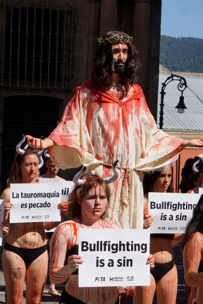Blutverschmierter Jesus mit blutbeschmierten Stieren vor dem Rathaus in Pamplona