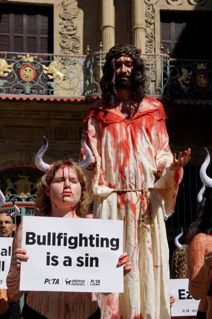 Blutverschmierter Jesus mit blutbeschmierten Stieren vor dem Rathaus in Pamplona